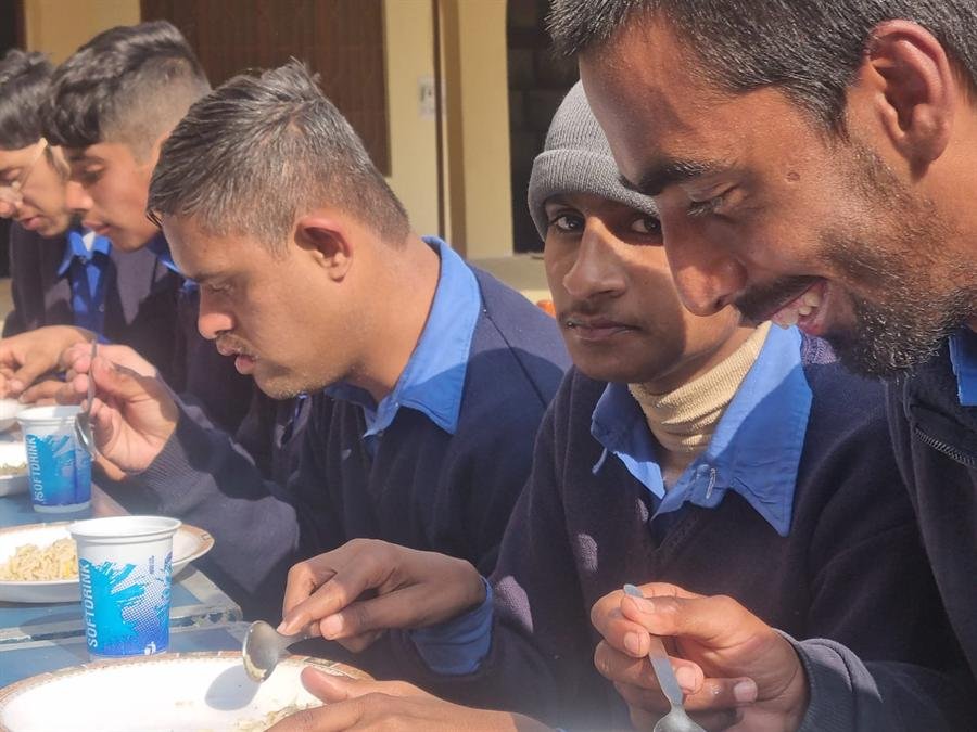 Students eating from plates with spoons at a table