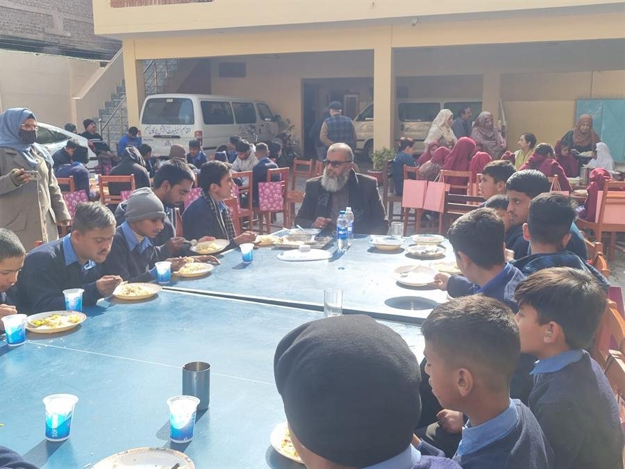 Students and staff sharing a meal at long tables in the school courtyard