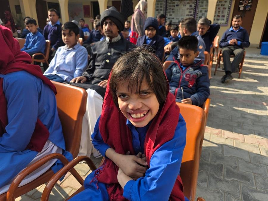 A smiling student in a red shawl at an outdoor gathering