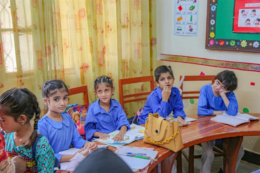 Young students seated at their classroom desks, some smiling at the camera