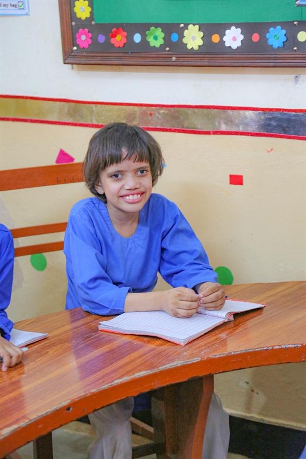 A smiling student sitting at a desk with an open notebook
