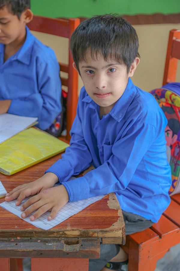 A student at a desk looking up at the camera