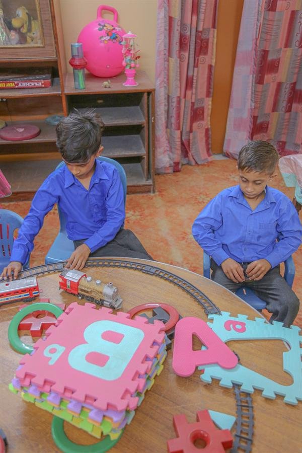 Two students playing with a toy train and foam alphabet mats