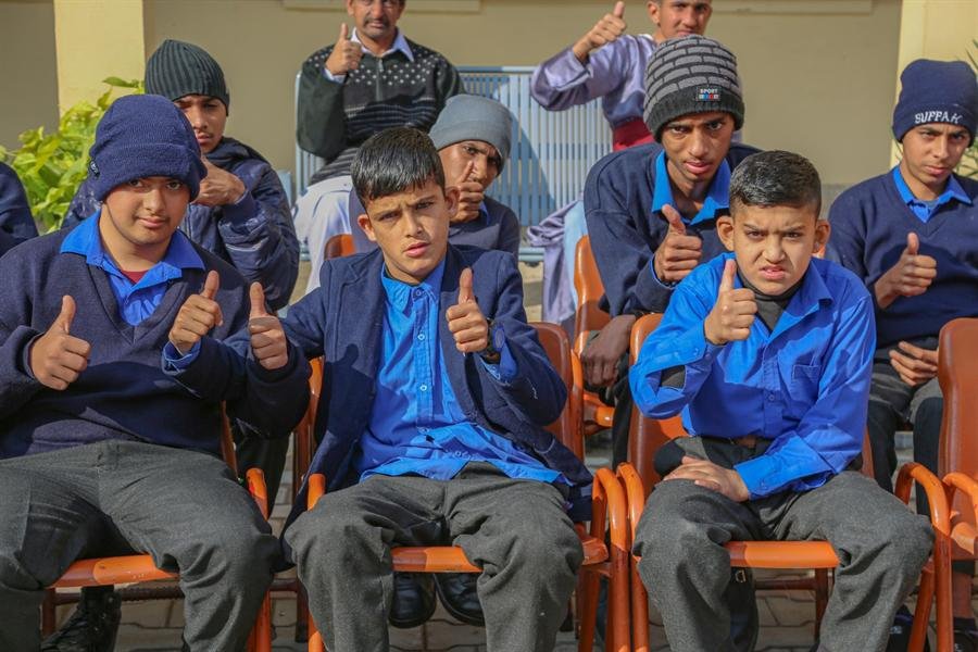 Students in school uniform seated in a row giving thumbs-up to the camera