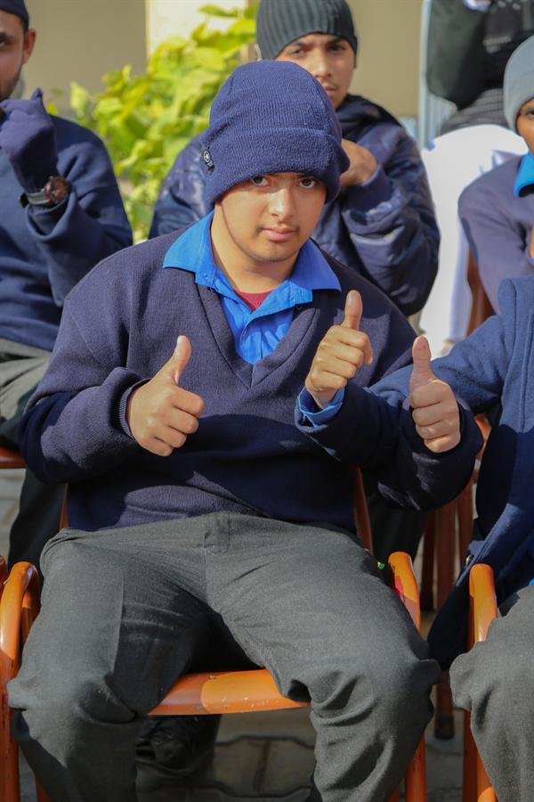 A student in a woolly hat giving two thumbs-up