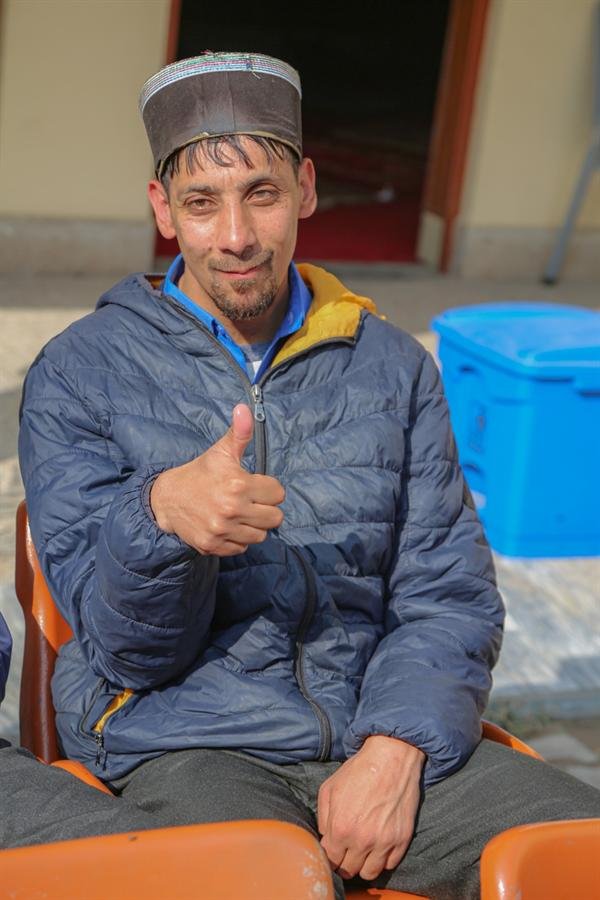 A smiling student in a padded jacket giving a thumbs-up