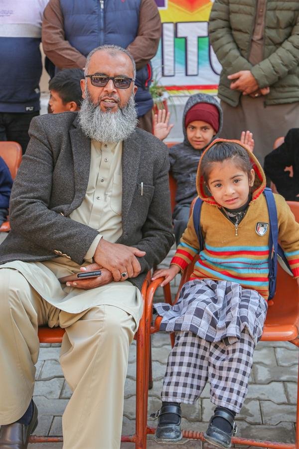 An older man seated beside a young child at an outdoor gathering