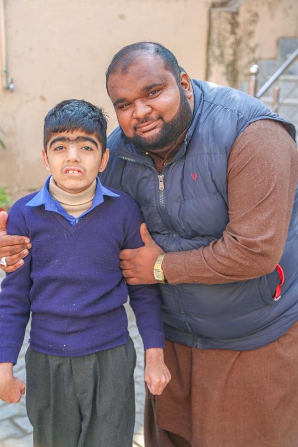 A student standing beside a smiling man with an arm around their shoulder