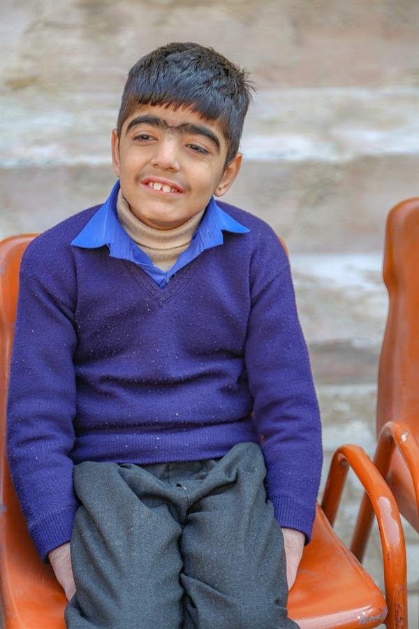A smiling student in a navy sweater seated on a chair